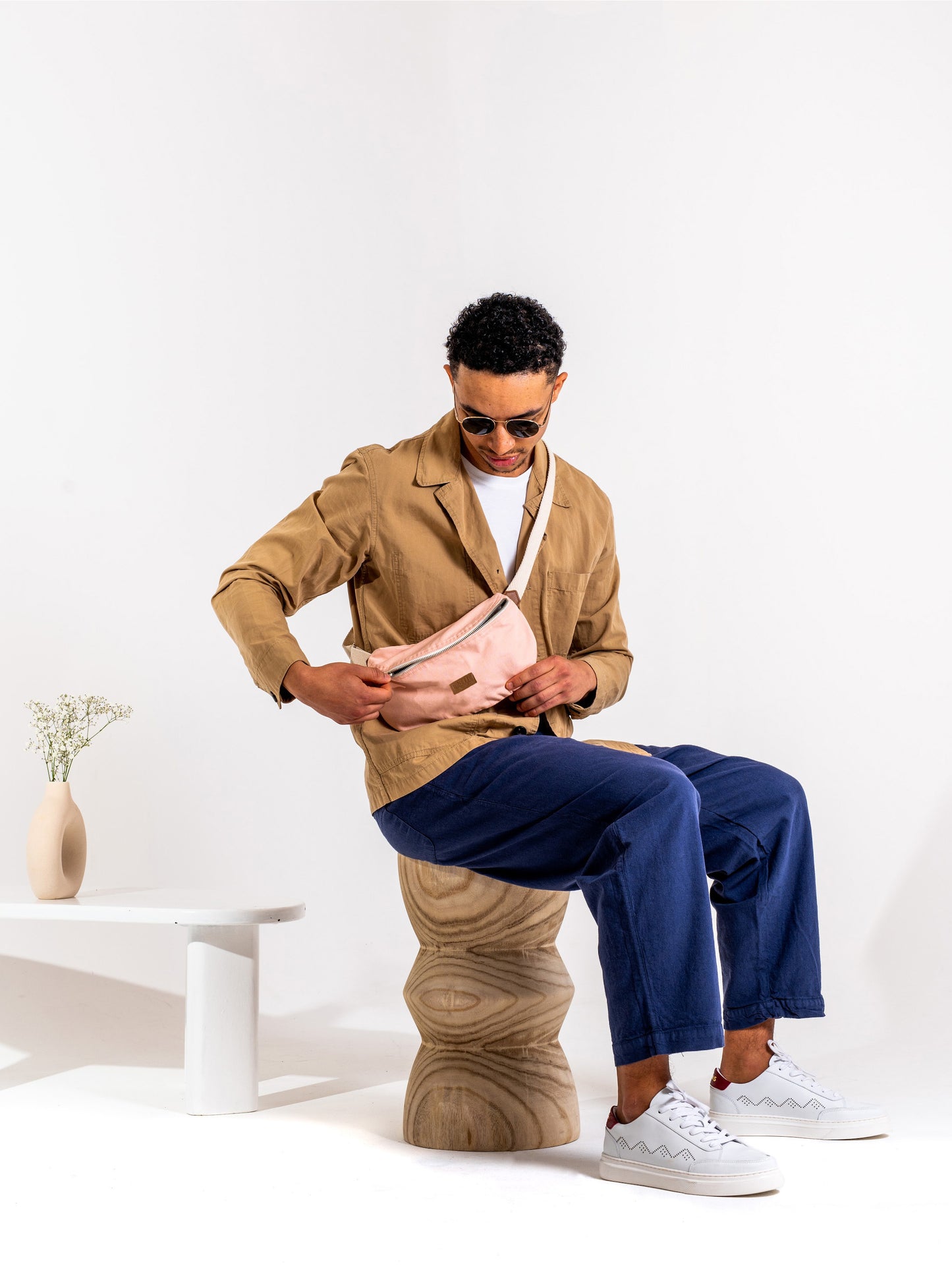 Jeune homme brun portant un Sac banane Binette upcyclé écoresponsable rose pâle collection binette x perus fabriqué à partir de chutes de tissus voués à être jetés ou brûlés et revalorisés par Binette la marque française écoresponsable de sacs banan eupcyclés et accessoires upcyclés ultra tendances, pratique, jolis, éthiques, durables, ecoresponsable, avec un faible impact environnemental, tout en luttant ocntre le gaspillage textile