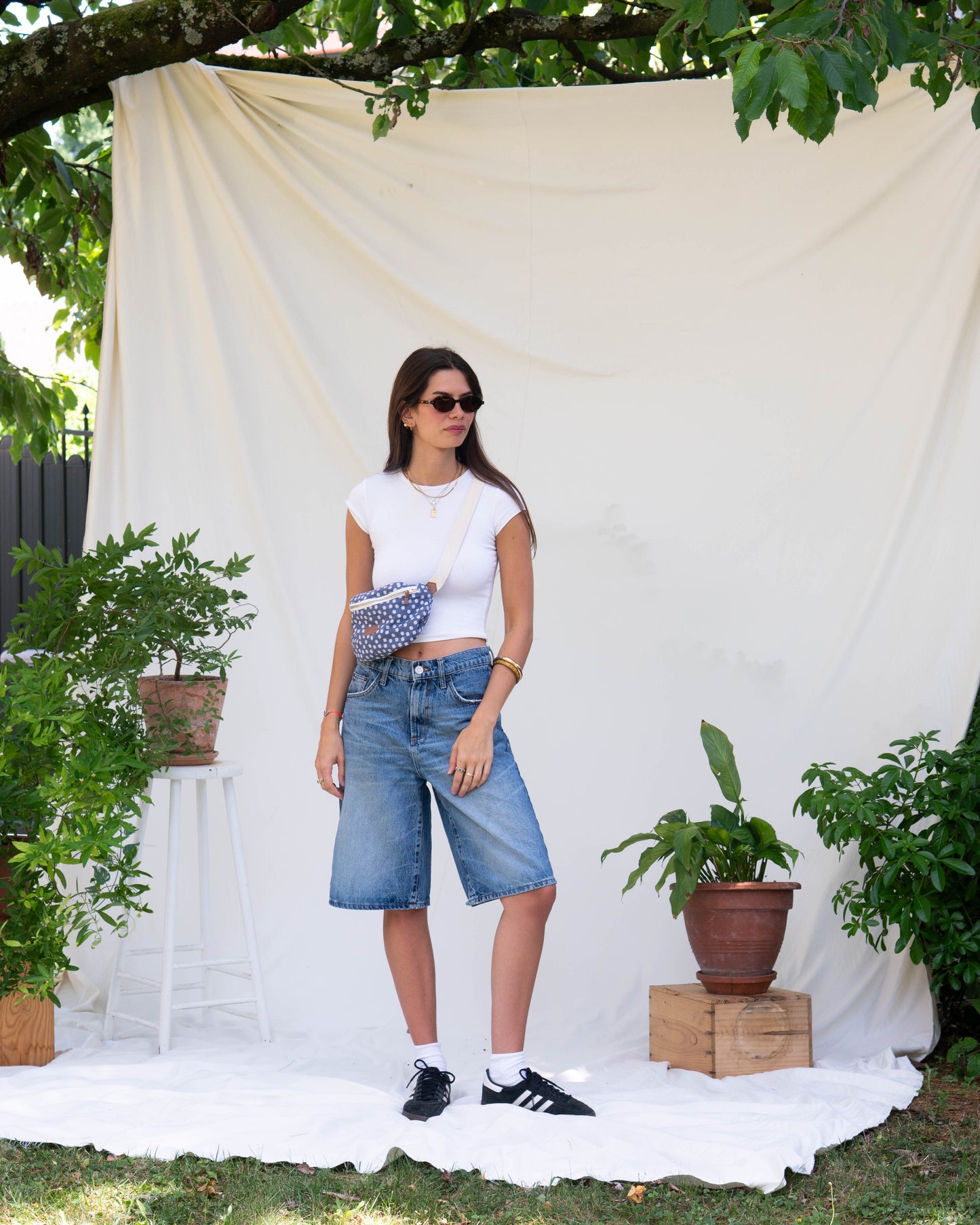 Sac banane bleu jean marguerite fleuri porté sur une jeune femme dans une cadre photo fleuri arbre