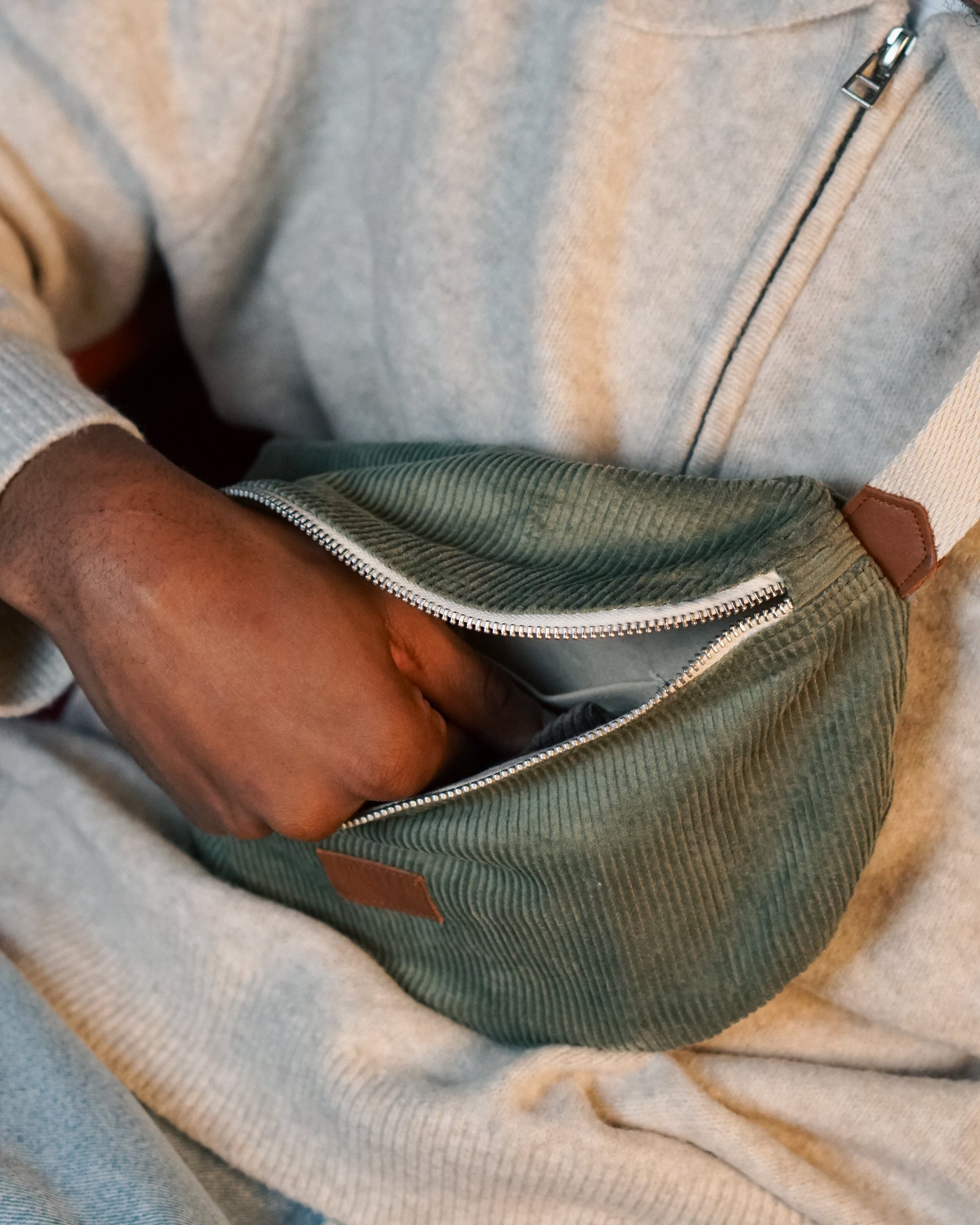 Modèle avec main dans la banane en velours côtelé vert écoresponsable avec sangle ajustable – Un accessoire durable et tendance, conçu à partir de matières upcyclées pour un look rétro et intemporel.