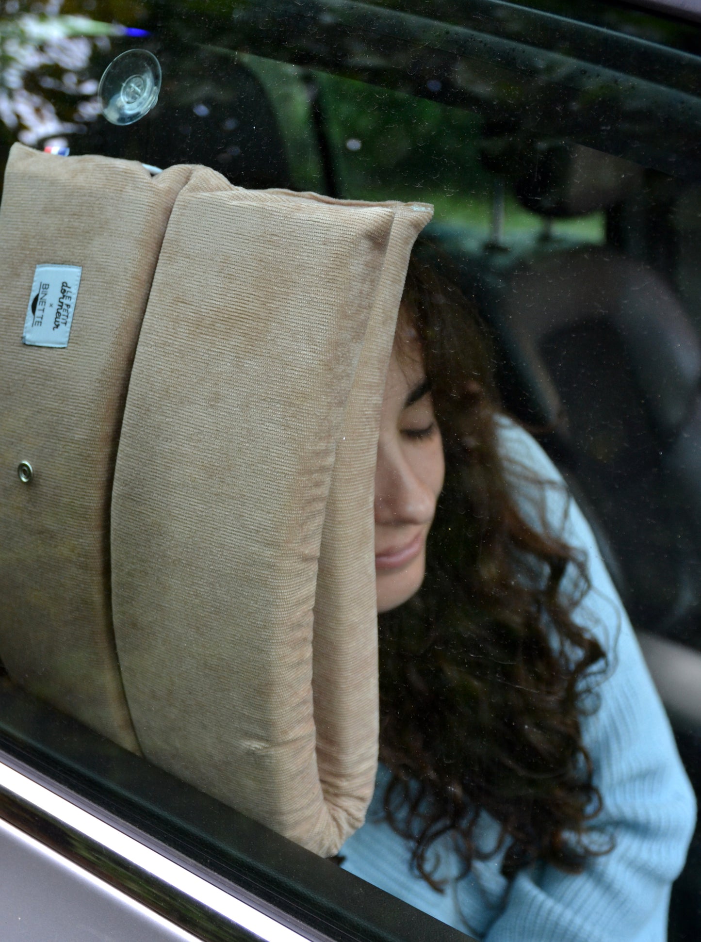 Modèle dormant sur le coussin rose Le Petit Dormeur x Binette accroché sur la vitre grâce à la ventouse.
Coussin pratique, utilisable de plusieurs manières pour passer un trajet reposant.
