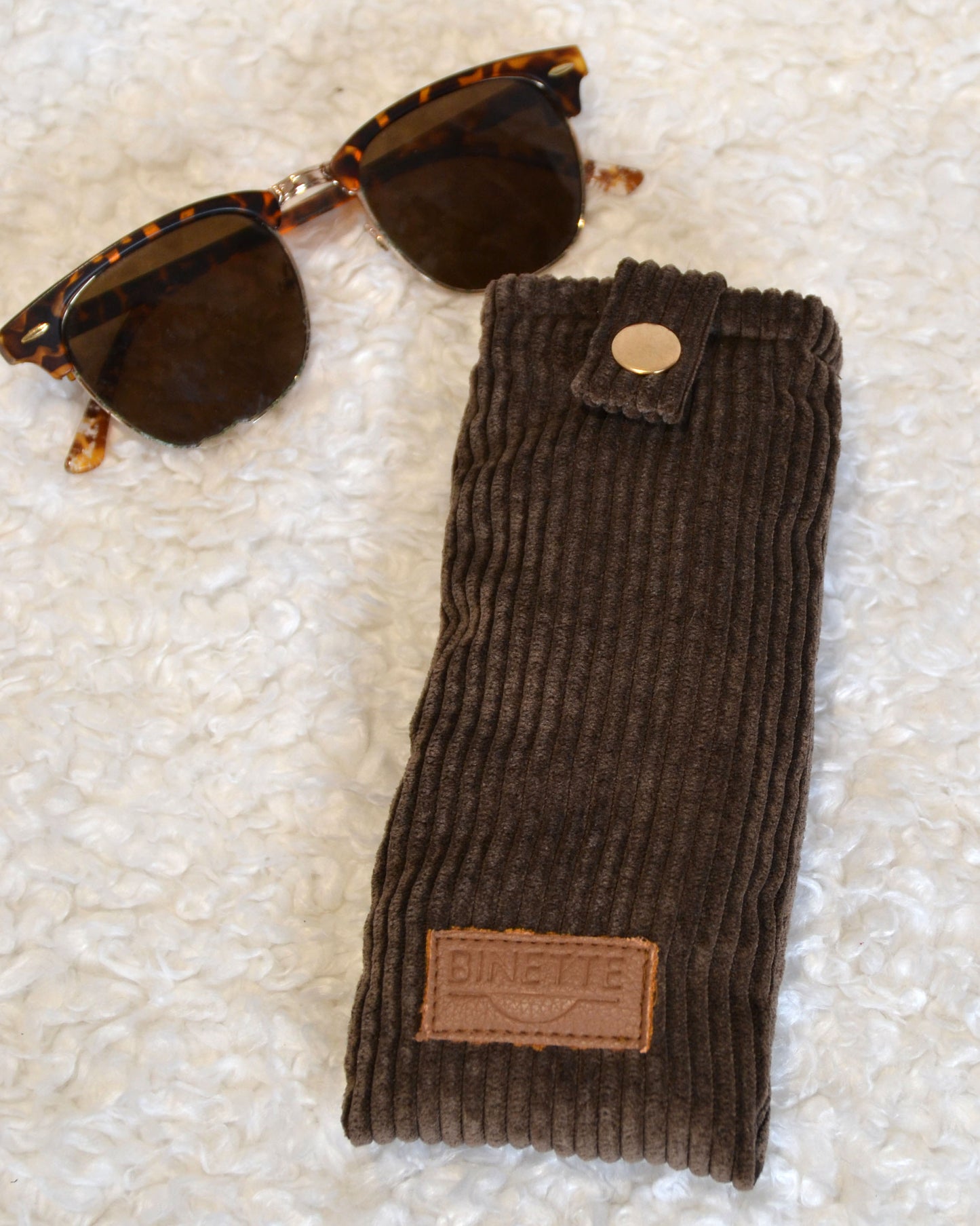 Étui à lunette marron chocolat velours côtelé avec paire de lunette marron sur moumoute blanche
