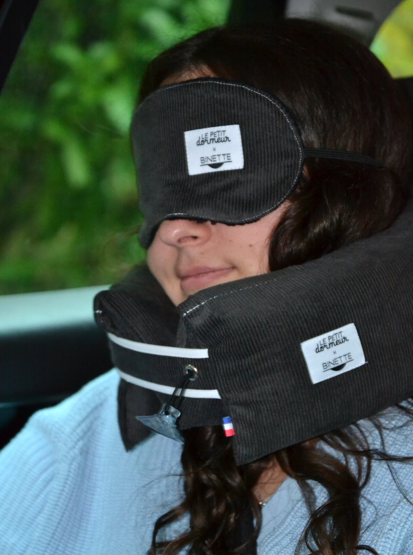 Modèle dormant paisiblement et portant le masque de sommeil et le coussin de voyage ergonomique en velours côtelé gris foncé lors d'un trajet en voiture.
Cet ensemble est conçu pour un confort optimal tout en respectant l’environnement.