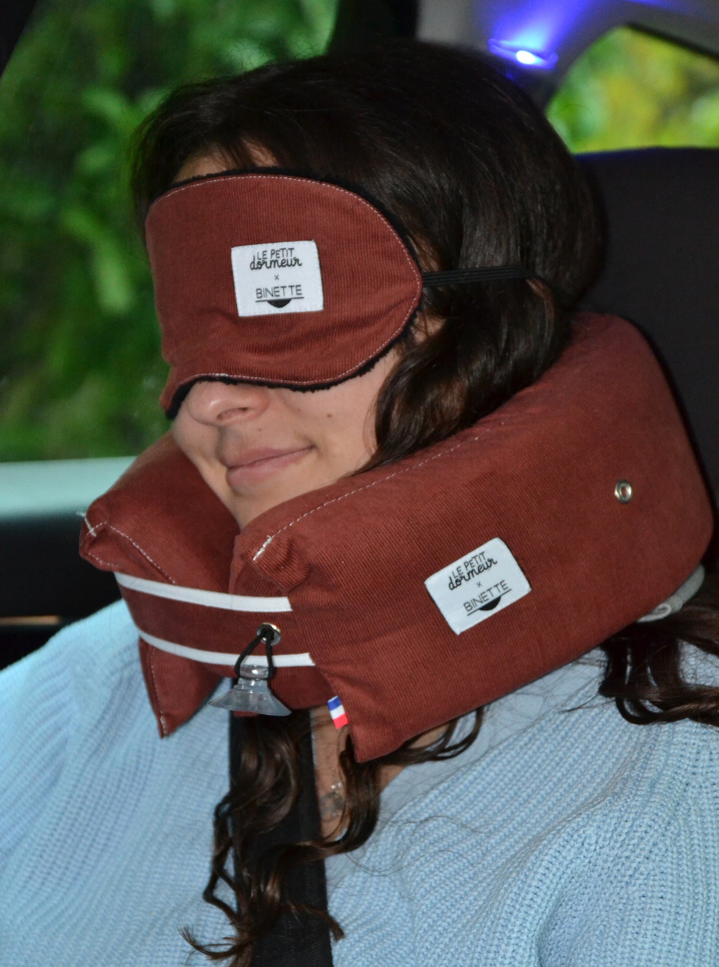 Modèle dormant paisiblement et portant le masque de sommeil et le coussin de voyage ergonomique en velours côtelé rouge lors d'un trajet en voiture.
Cet ensemble est conçu pour un confort optimal tout en respectant l’environnement.