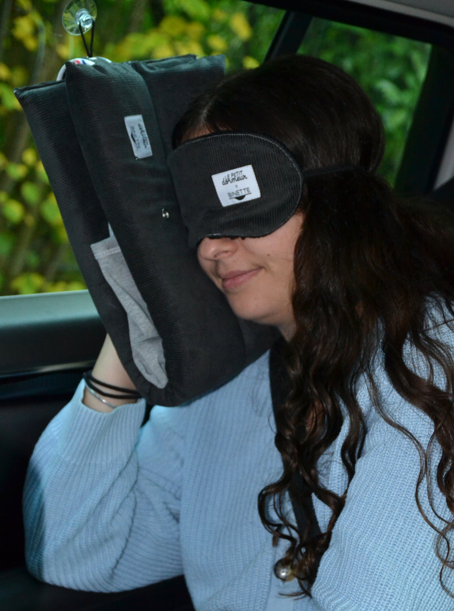 Modèle portant le masque de sommeil sur les yeux et le coussin de voyage ergonomique en velours côtelé gris lors d'un trajet en voiture.
Cet ensemble est conçu pour un confort optimal tout en respectant l’environnement.