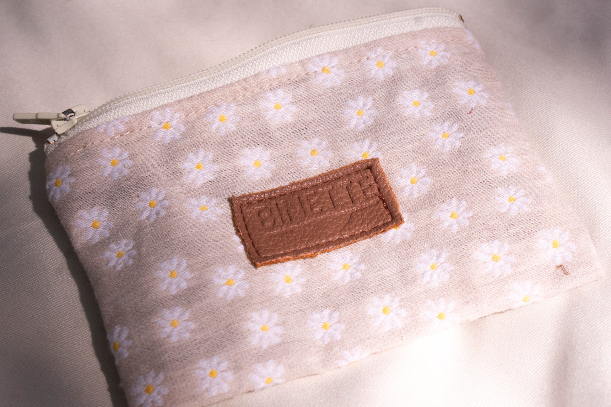 Packshot zoomé pochette binette ouverte beige verte avec motif marguerite.