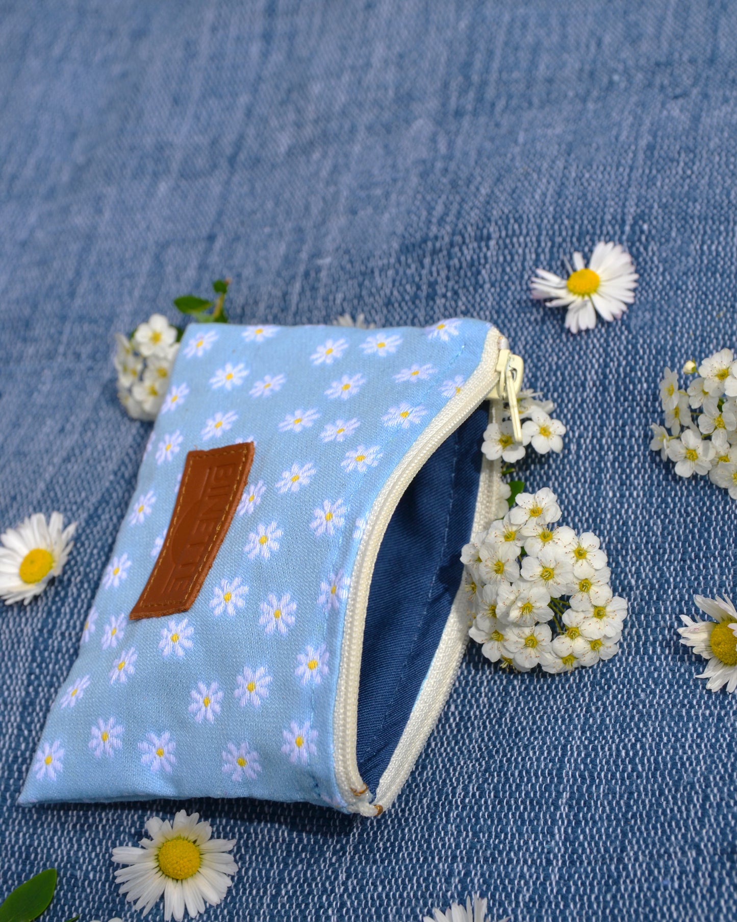 Cette photo met en avant la Pochette Marguerite Bleue, soulignant sa complémentarité avec la Binette assortie. Son style bohème et élégant s'accorde parfaitement avec celui de la Binette, créant ainsi un ensemble harmonieux et tendance.