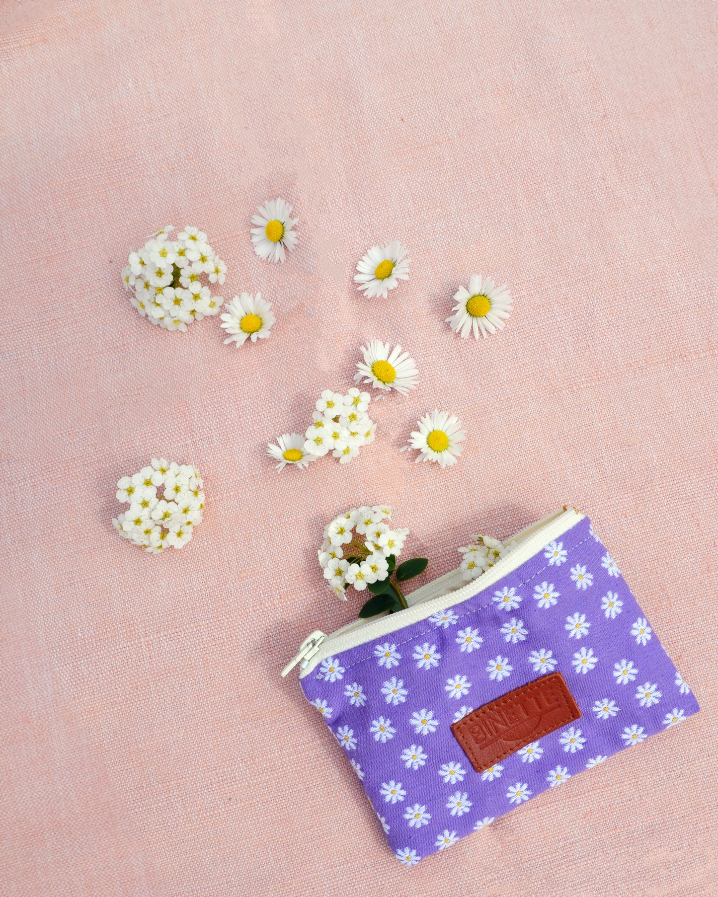 La Pochette Marguerite Violette se dévoile dans toute sa splendeur dans cette photo en gros plan. Son motif floral délicat et sa couleur violette captivent le regard, ajoutant une touche de charme bohème à cet accessoire polyvalent.