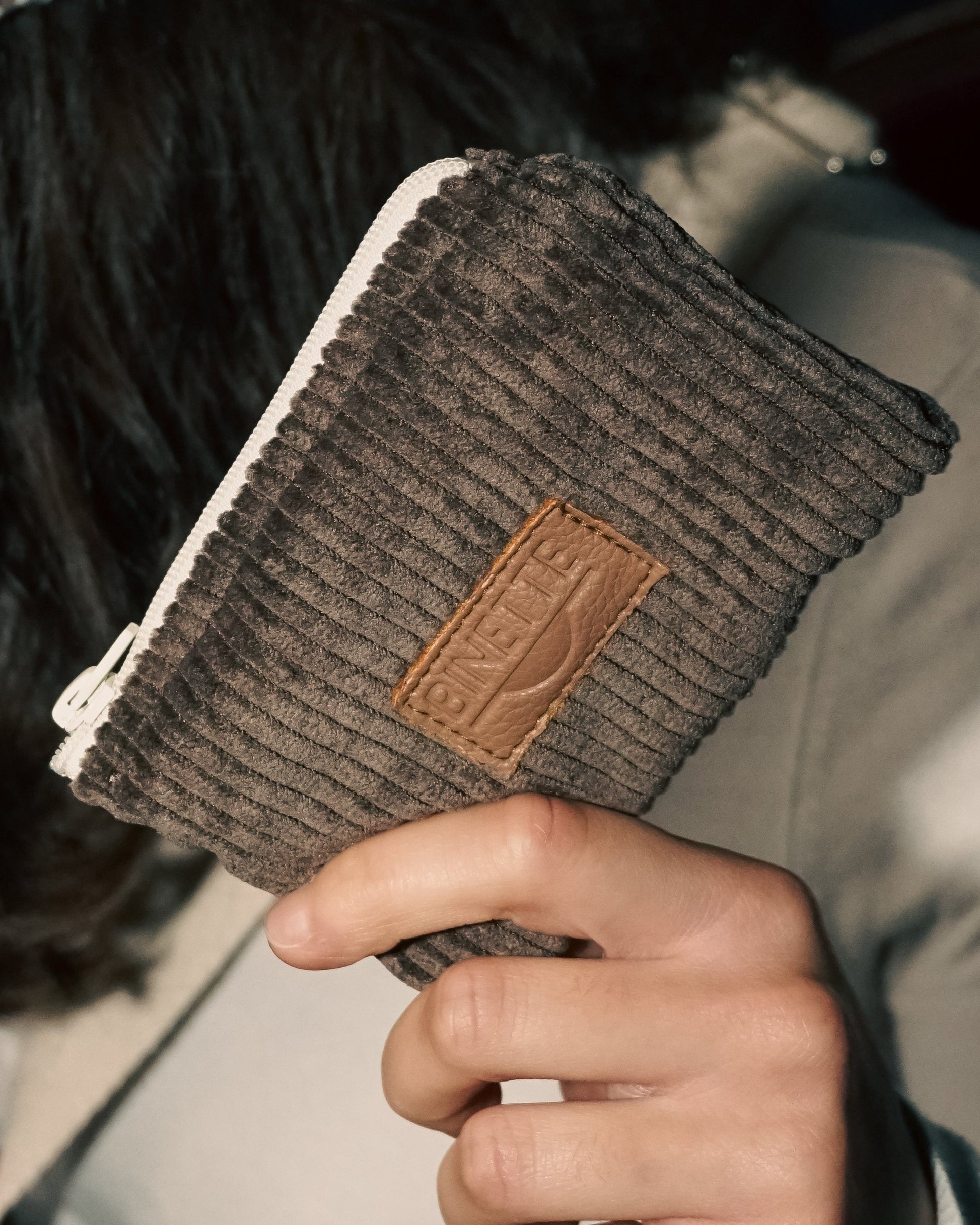 Modèle tenant porte monnaie marron chocolat velours côtelé dans sa main
