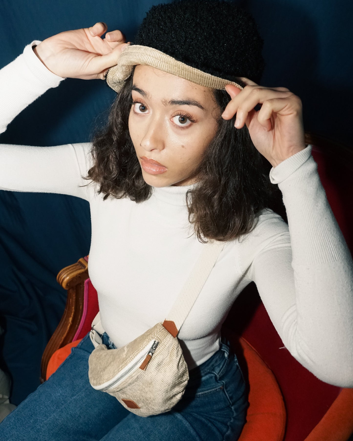 Modèle regardant l'objectif et portant un bob réversible noir et beige sable et une banane Binette couleur beige sable en velours côtelé.