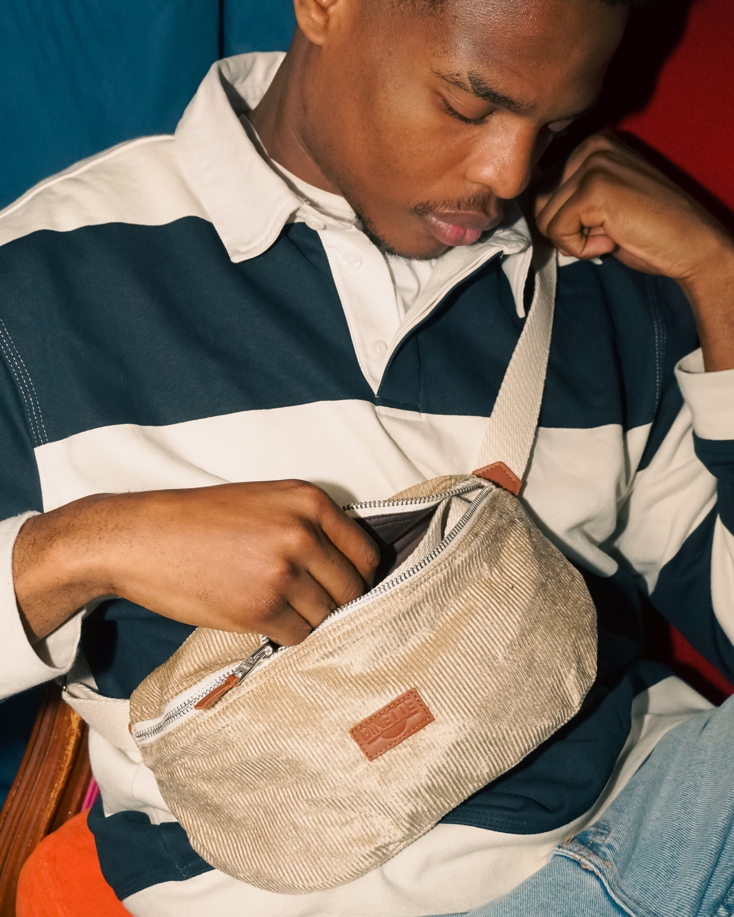 Jeune homme portant un Sac banane beige sable en velours côtelé regardant la banane. Binette marque française et écoresponsable de sacs banane upcyclés fabriqués à partir de chutes de tissus dormants voués à être jetés ou brûlés et revalorisés en sacs banane et accessoires de la vie quotidienne ultra tendances, pratiques, éthiques, jolis, durables, avec un faible impact environnemental tout en luttant contre le gaspillage textile.