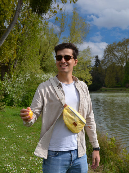 Jeune homme brun portant un sac banane binette écoresponsable jaune motif vichy  fait par une marque française. 