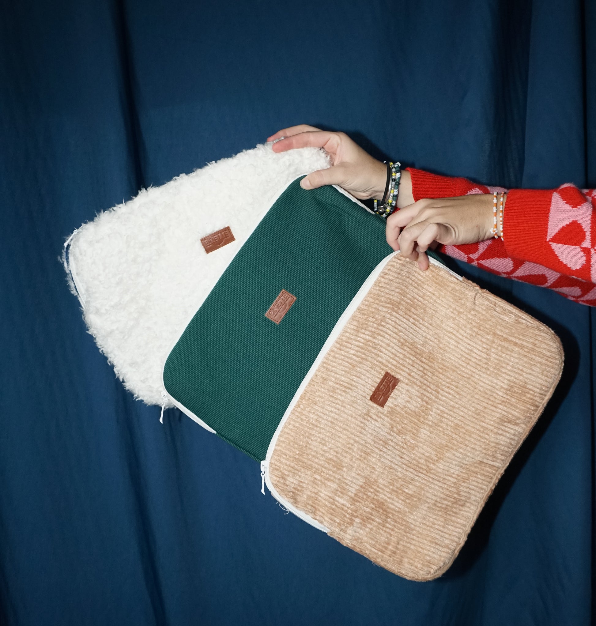 Ensemble de trois pochettes d'ordinateur écoresponsables : une en velours côtelé rose satiné, une en velours vert sapin et une en moumoute blanche toute douce. Conçues à partir de matériaux upcyclés et fabriquées en France, elles allient style, résistance et engagement durable