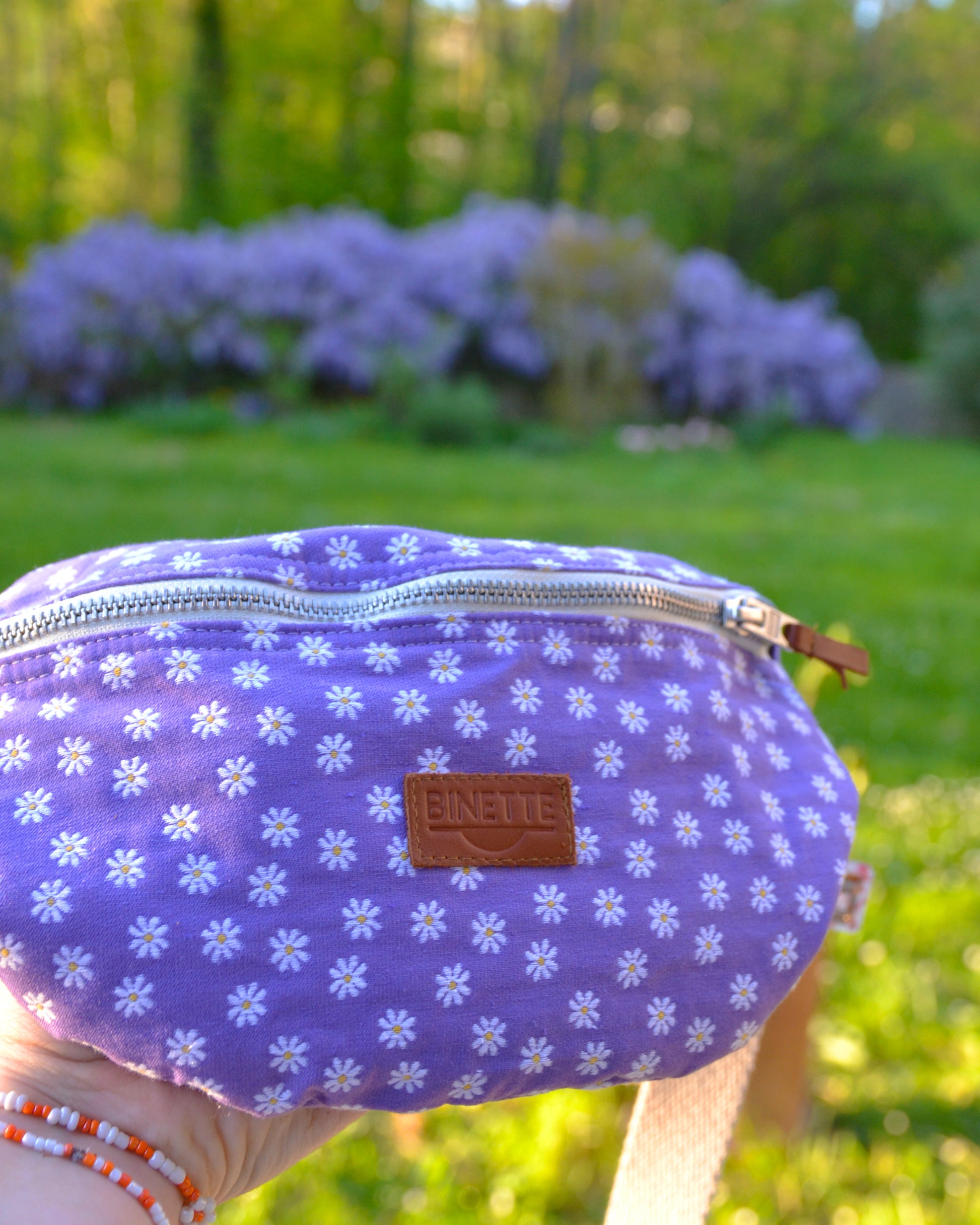 Découvrez le sac banane Marguerite Violette dans toute sa splendeur ! Cette photo en gros plan met en valeur son motif floral éclatant et sa couleur violette vibrante. Pratique et stylé, ce sac devient rapidement un indispensable de cette saison estivale.