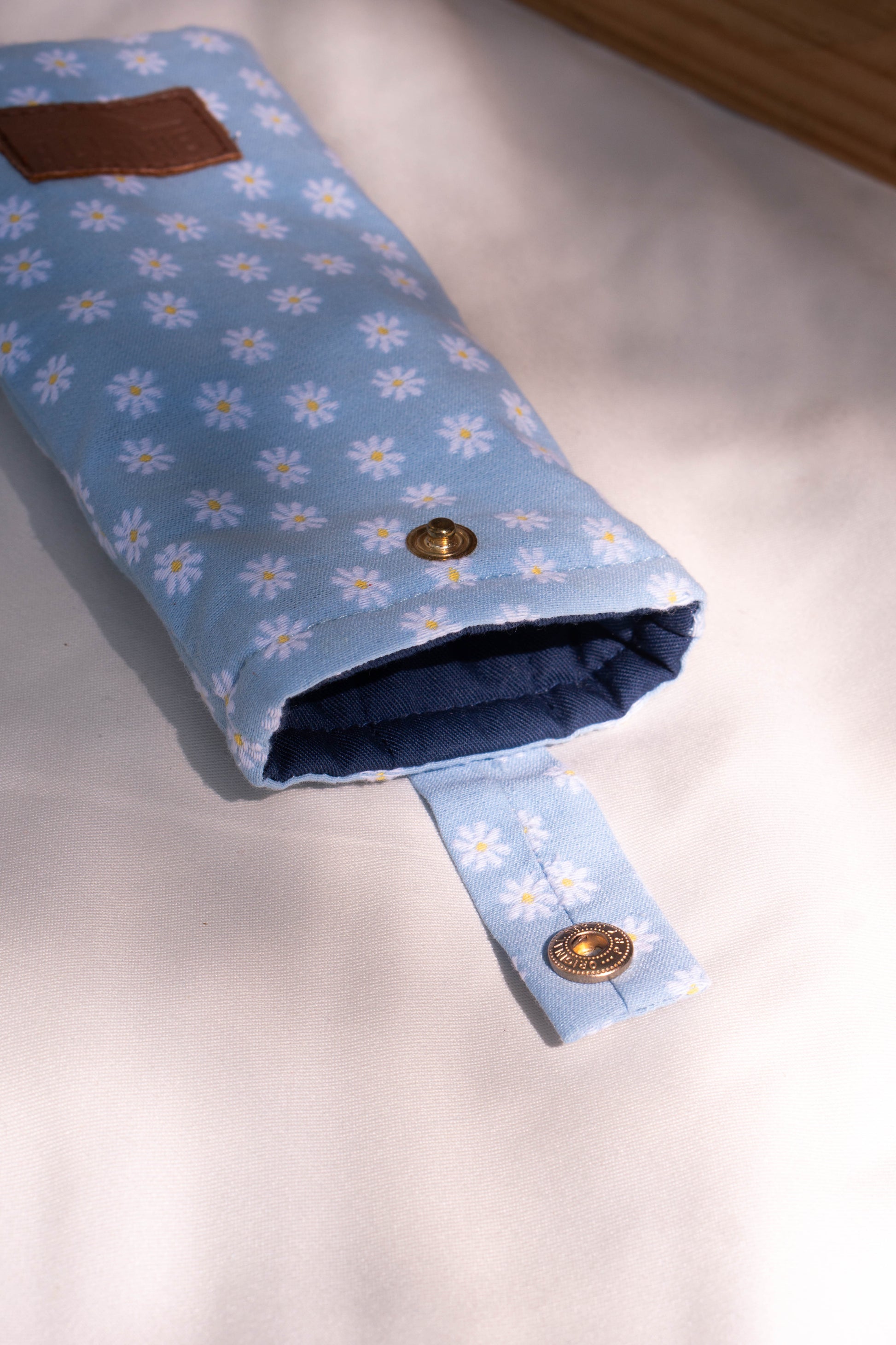 Packashot avec l'étui à lunettes bleu ciel marguerites. Design raffiné et détails soignés qui ajoutent une touche de sophistication à la protection de vos lunettes.