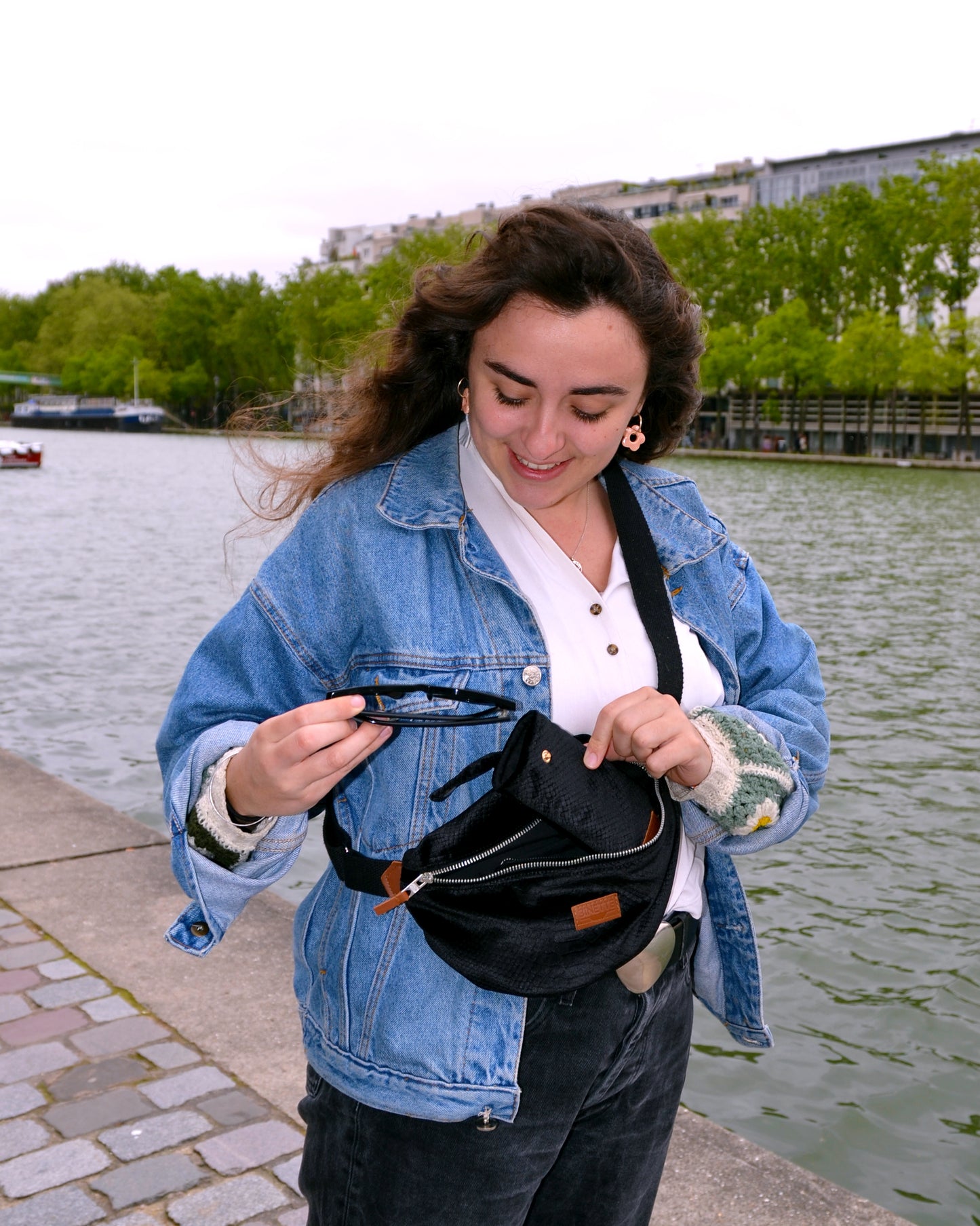 jeune femme portant un sac banane upcyclé écoresponsable croco en velours gaufré noir effet croco sur les quais de seine parisien de la marque Binette une marque de sacs banane écoresponsable supcyclés et accessoires upcyclés et sacs cabas et sacs banane dei-lune made in france