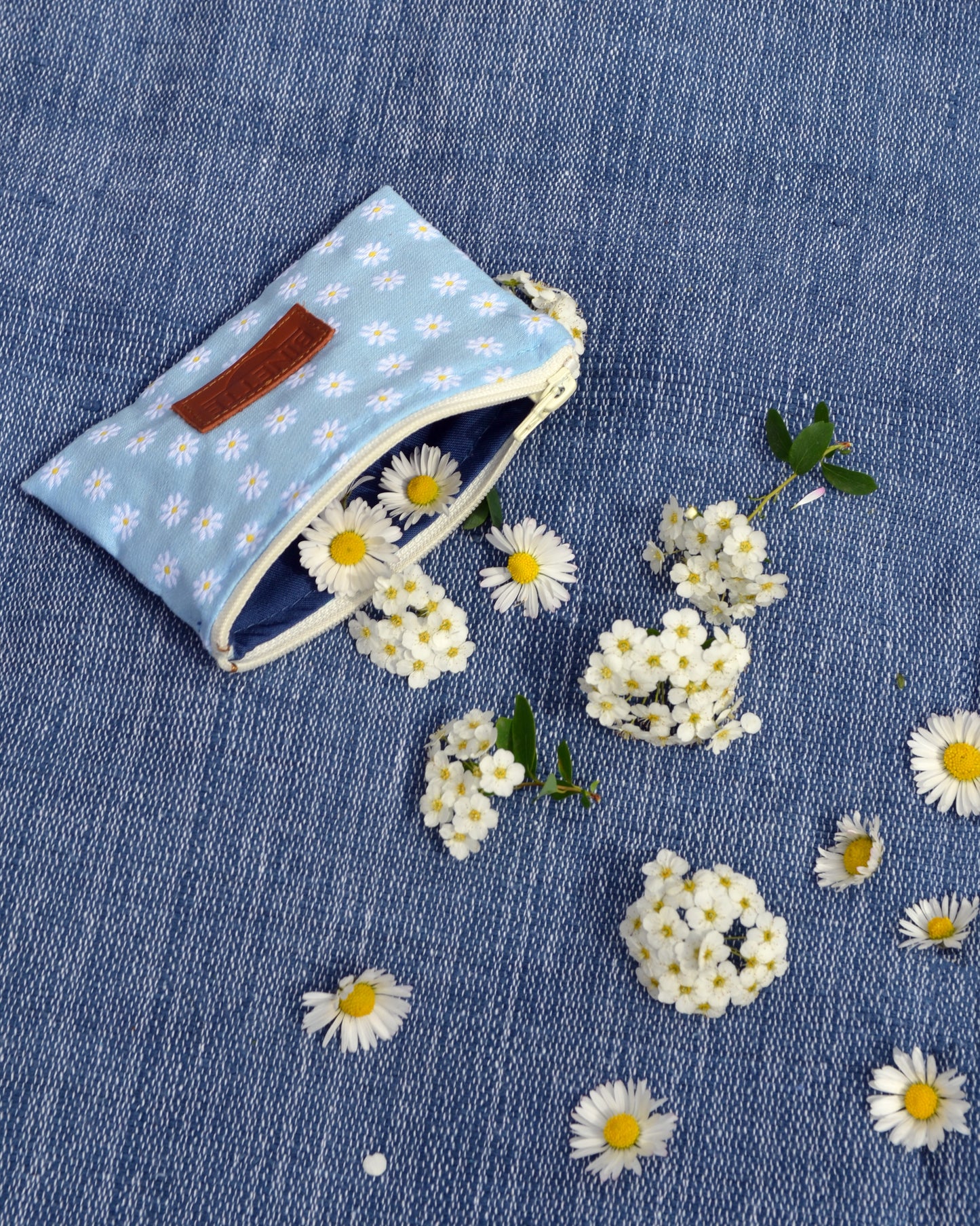 Cette première photo met en valeur la polyvalence de la Pochette Marguerite Bleue. Que ce soit comme mini porte-monnaie, trousse de secours ou "fourre-tout", cette pochette est l'accessoire idéal pour accompagner vos aventures du quotidien. Son style bohème et élégant lui permet de s'accorder avec toutes vos tenues, ajoutant une touche de charme à votre look.