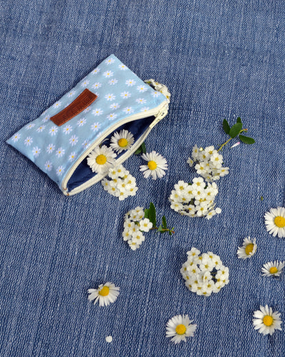 Cette première photo met en valeur la polyvalence de la Pochette Marguerite Bleue. Que ce soit comme mini porte-monnaie, trousse de secours ou "fourre-tout", cette pochette est l'accessoire idéal pour accompagner vos aventures du quotidien. Son style bohème et élégant lui permet de s'accorder avec toutes vos tenues, ajoutant une touche de charme à votre look.