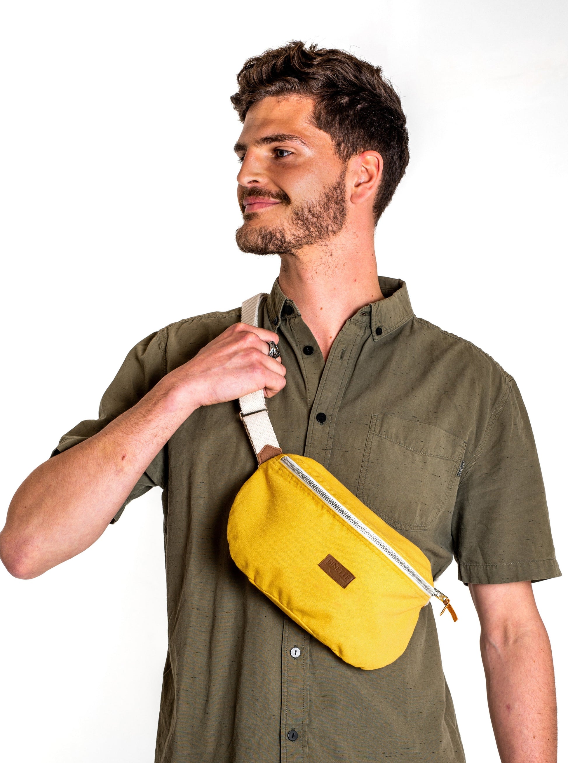 Jeune homme brun portant un Sac banane Binette upcyclé à partir de chutes de tissus dormants voués à être jetés ou brûlés revalorisés par Binette la marque française écoresponsable de sacs banane et accessoires écoreponsables, éthiques, tendances, jolis, ecoresponsable, avec un faible impact environnemental et luttant contre le gaspillage textileécoresponsable pour un sac banane upcyclé jaune collection binette x perus