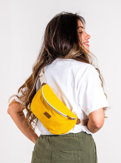 Jeune femme brune portant un Sac banane Binette upcyclé à partir de chutes de tissus dormants voués à être jetés ou brûlés revalorisés par Binette la marque française écoresponsable de sacs banane et accessoires écoreponsables, éthiques, tendances, jolis, ecoresponsable, avec un faible impact environnemental et luttant contre le gaspillage textileécoresponsable pour un sac banane upcyclé jaune collection binette x perus