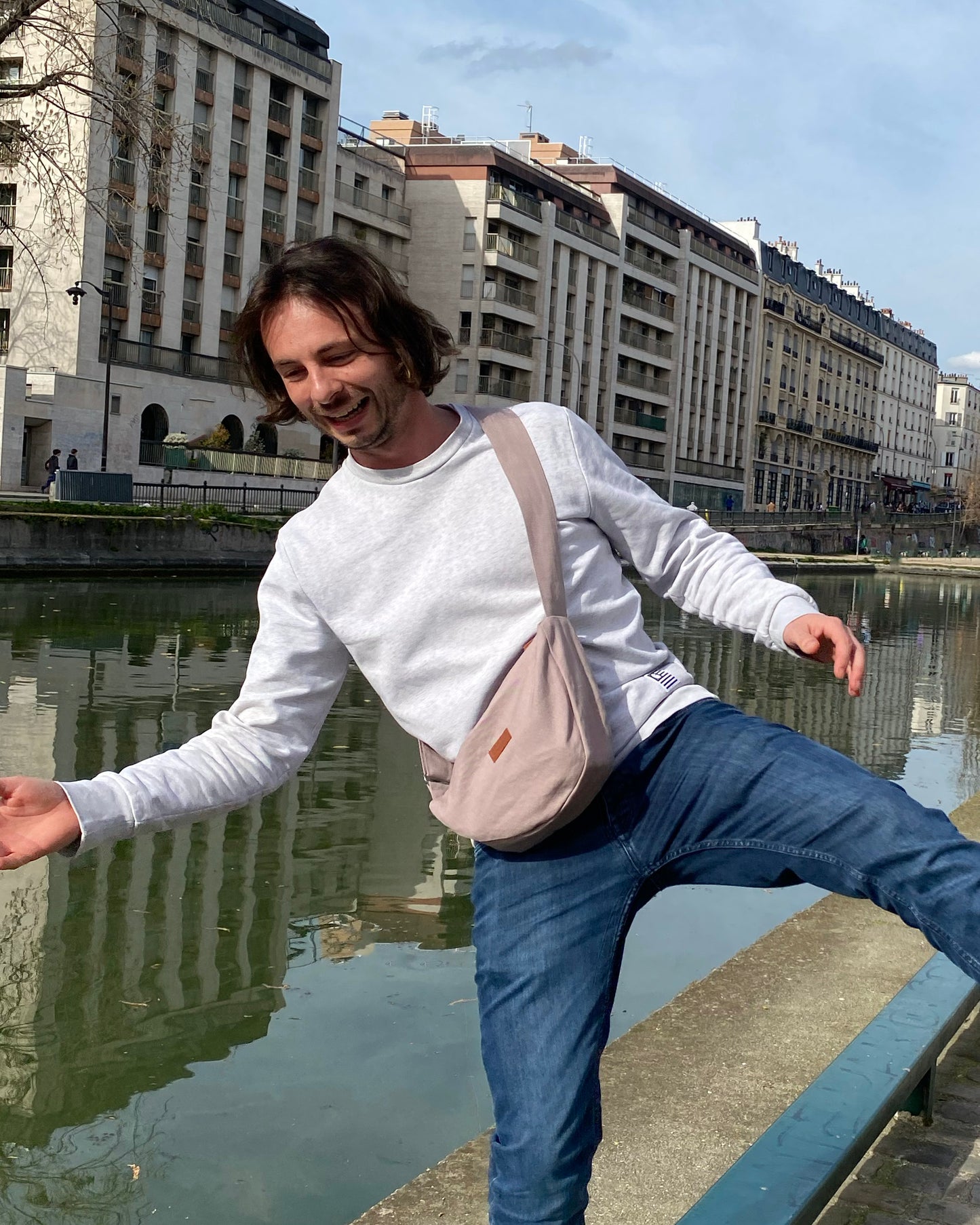 Capturant l'esprit de l'aventure urbaine, un homme dynamique porte fièrement le Sac Banane Demi-Lune gris lilas. Son attitude détendue témoigne de la polyvalence de ce sac, qui peut être porté de différentes manières selon les préférences personnelles. Avec sa contenance généreuse et son design éco-responsable, ce sac devient rapidement un compagnon de choix pour toutes les explorations citadines.