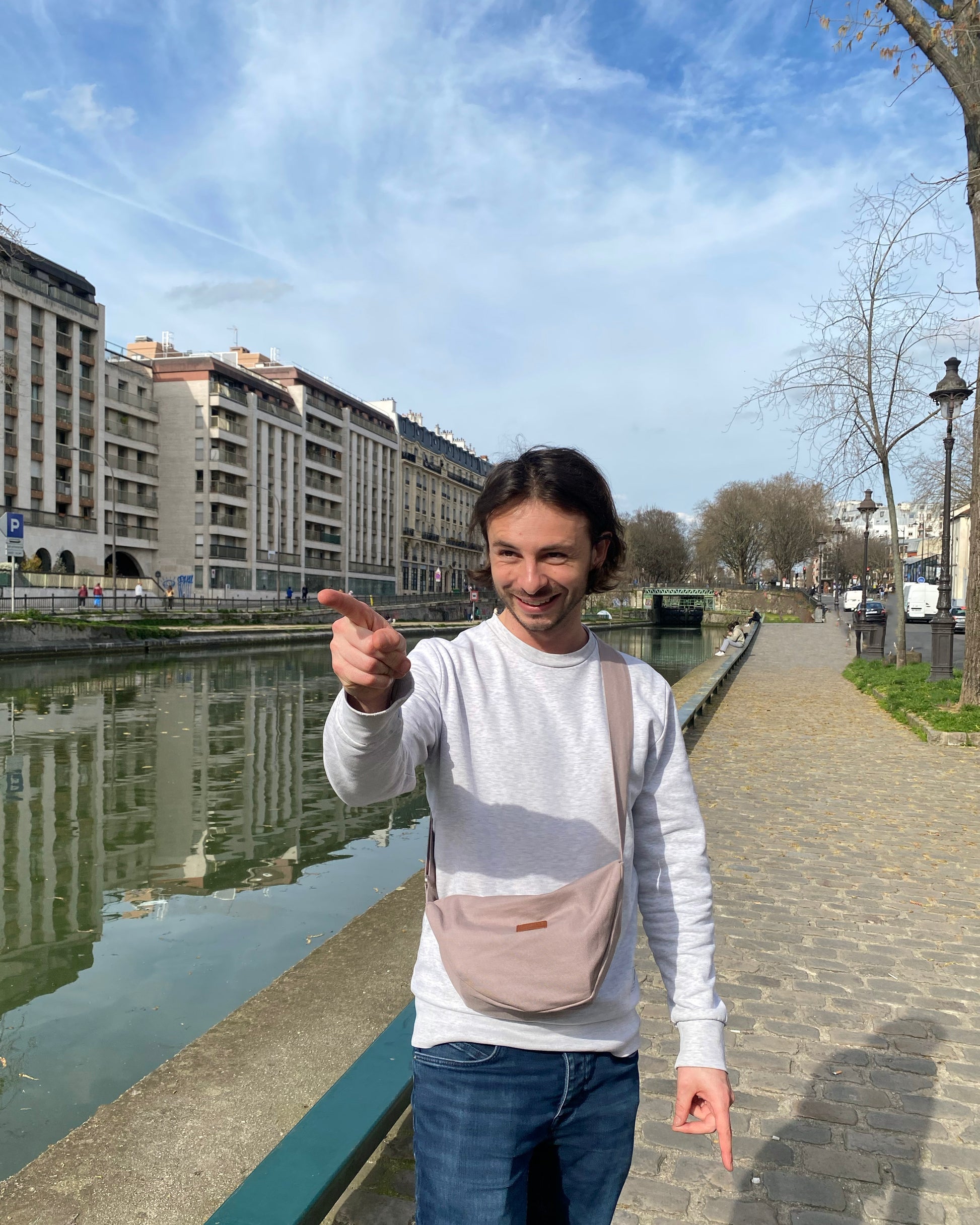 Dans cette scène urbaine, un homme affiche avec confiance le Sac Banane Demi-Lune gris lilas, ajoutant une touche de modernité à son look. Son attitude décontractée témoigne de la praticité de ce sac, qui lui permet de garder l'essentiel à portée de main tout en restant élégant. Avec son design épuré et sa fabrication éthique, ce sac devient rapidement un accessoire incontournable pour les hommes urbains à la recherche de style et de fonctionnalité.