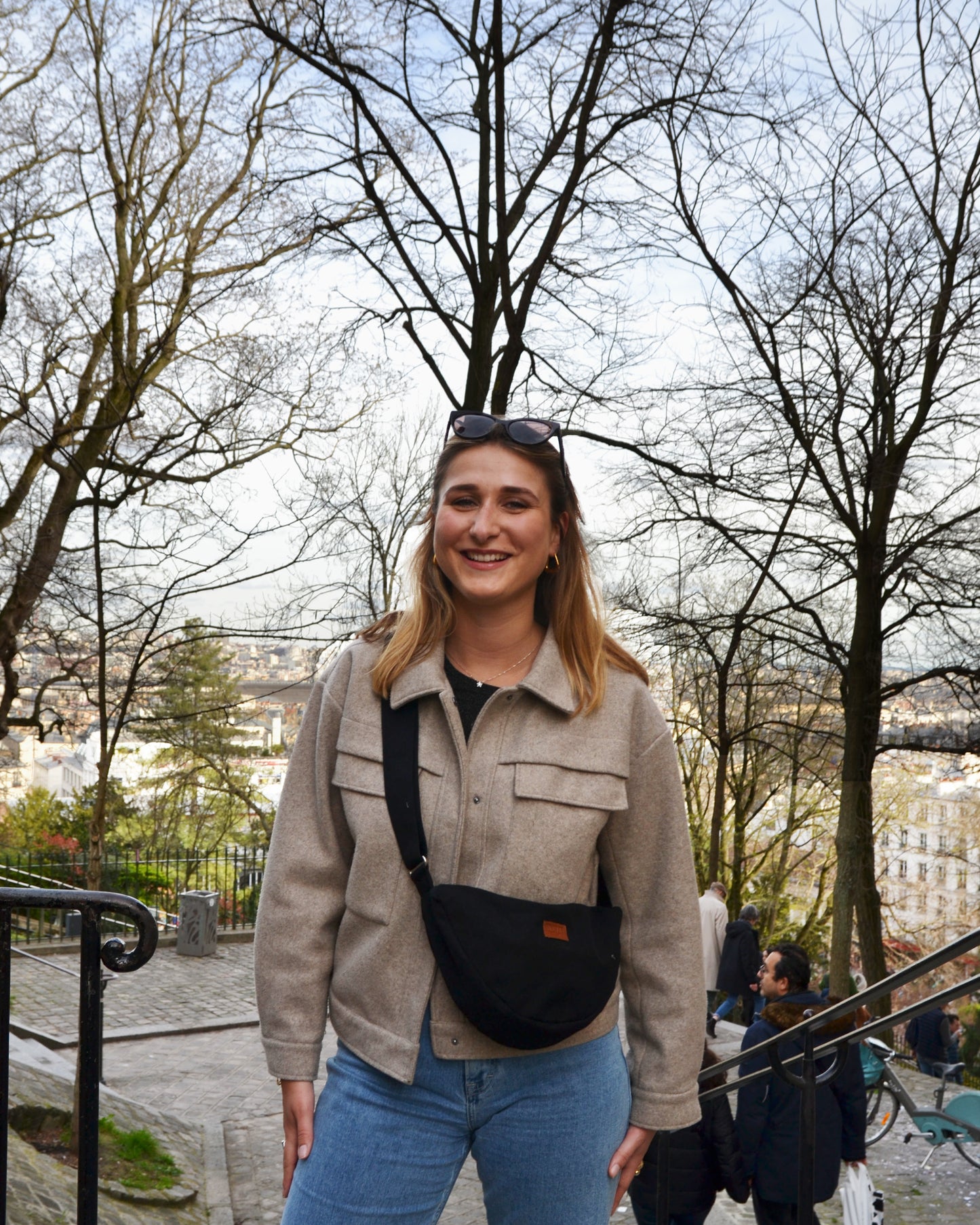 Capturant l'esprit de l'aventure urbaine, une femme dynamique porte fièrement le Sac Banane Demi-Lune, illustrant sa praticité dans toutes les situations. Son sourire insouciant témoigne du confort et de la liberté de mouvement offerts par ce sac, qui lui permet de garder l'essentiel à portée de main tout en restant stylée. Avec son design épuré et son histoire éthique, ce sac devient un symbole de mode responsable et de style urbain.