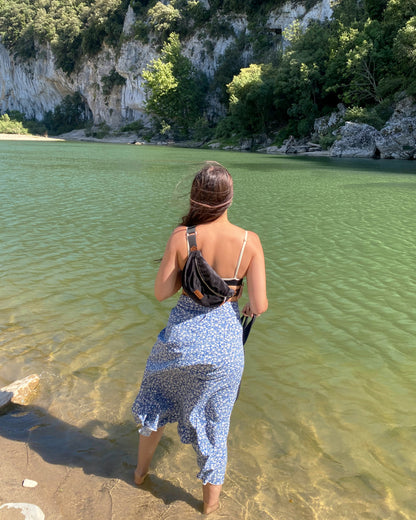 une femme au lac de come porte avec grâce la Binette Croco en velours gaufré noir upcyclé écoresponsable en bandoulière. Ce sac, qui lui permet de garder tous ses essentiels à portée de main en toute élégance. Avec son total look noir et son effet crocodile subtil, la Binette Croco devient rapidement un accessoire incontournable pour celles qui recherchent style et fonctionnalité.