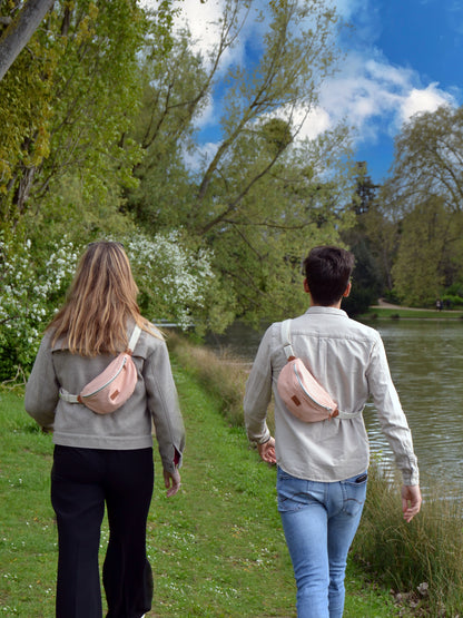 Jeune femme blonde et jeune homme brun portant un Sac bananae Binette Pivoine Rose pâle upcyclé fabriqué à partir de chutes de tissus dormants voués à être jetés ou brûlés et revalorisé par Binette la marque française de sacs banane et accessoires upcyclés pour en aire des sacs banane et accessoires pratiques, tendances, éthiques, ecoresponsable, durable, avec un impact environnemental faible et en luttant contre le gaspillage textile