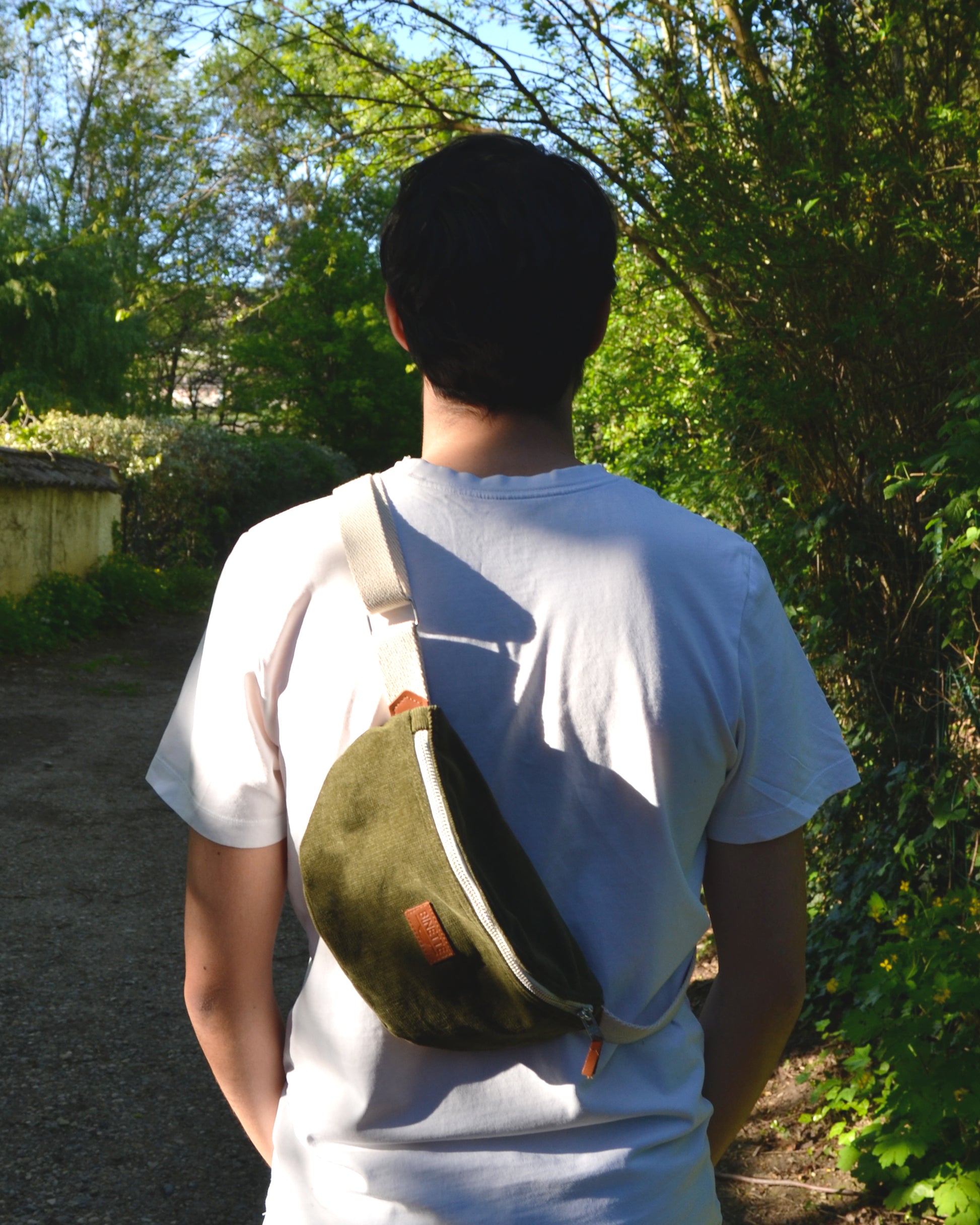 sac banane écoresponsable upcyclé tendance et unique de couleur vert velours côtelé vert de la marque française Binette marque de sacs banane sacs cabas sacs demi-lune et accessoires upcyclés écoresponsable photo d'un homme de dos dans un champs portant son sac banane Binette