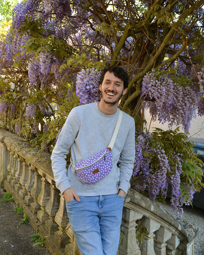 Dans cette scène dynamique, un homme arbore fièrement la Binette Marguerite Violette en bandoulière, ajoutant une touche de couleur et de style à son look urbain. Son attitude décontractée et assurée démontre la polyvalence de ce sac, qui s'adapte parfaitement à tous les styles et toutes les occasions.