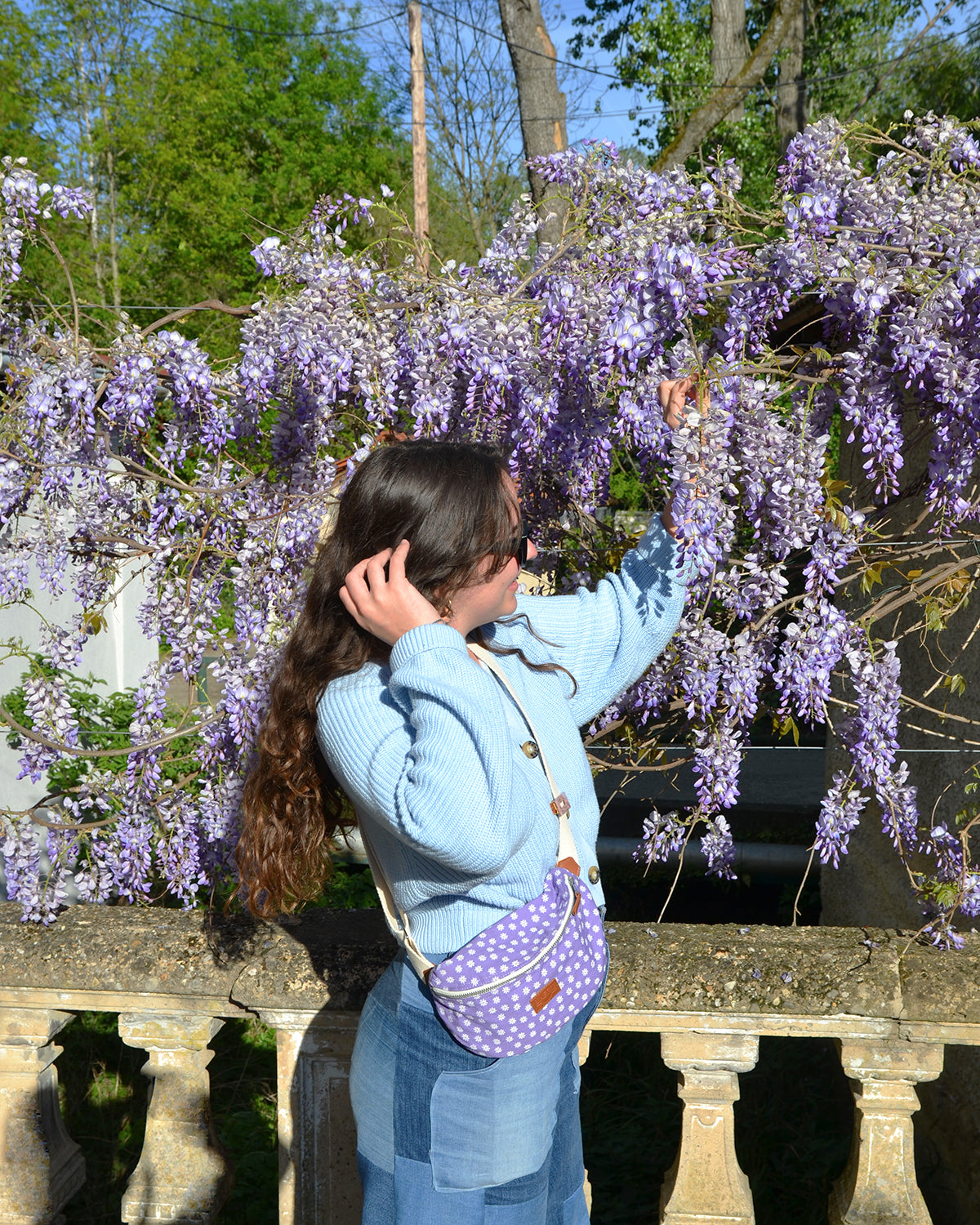 Cette image capture l'élégance décontractée d'une femme portant la Binette Marguerite Violette en bandoulière. Son allure confiante et décontractée témoigne de la praticité de ce sac, qui lui permet de rester stylée tout en gardant les mains libres. L'intérieur spacieux de la Binette offre suffisamment d'espace pour ranger tous ses essentiels, lui permettant de se déplacer avec aisance et style. Avec la Binette Marguerite Violette, le chic est à portée de main, où que vous alliez.