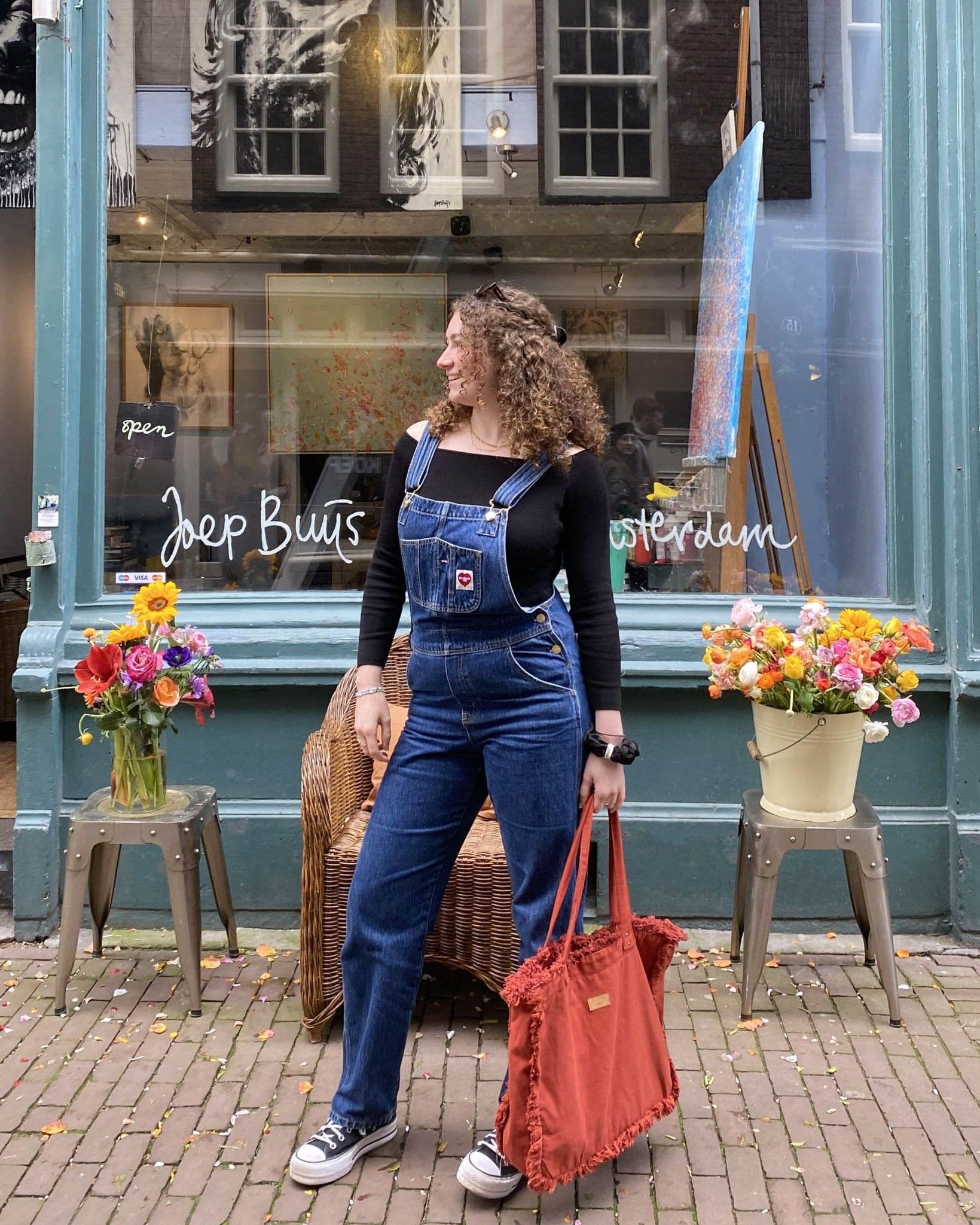 Cette image dynamique capture une femme moderne portant le Sac Cabas Rouge Terracotta lors d'une balade en ville. Son style chic et décontracté s'harmonise parfaitement avec la couleur vibrante du sac, ajoutant une touche de fraîcheur printanière à son look urbain. Avec sa grande capacité de rangement et sa fermeture éclair optionnelle, ce sac allie praticité et modernité avec élégance.