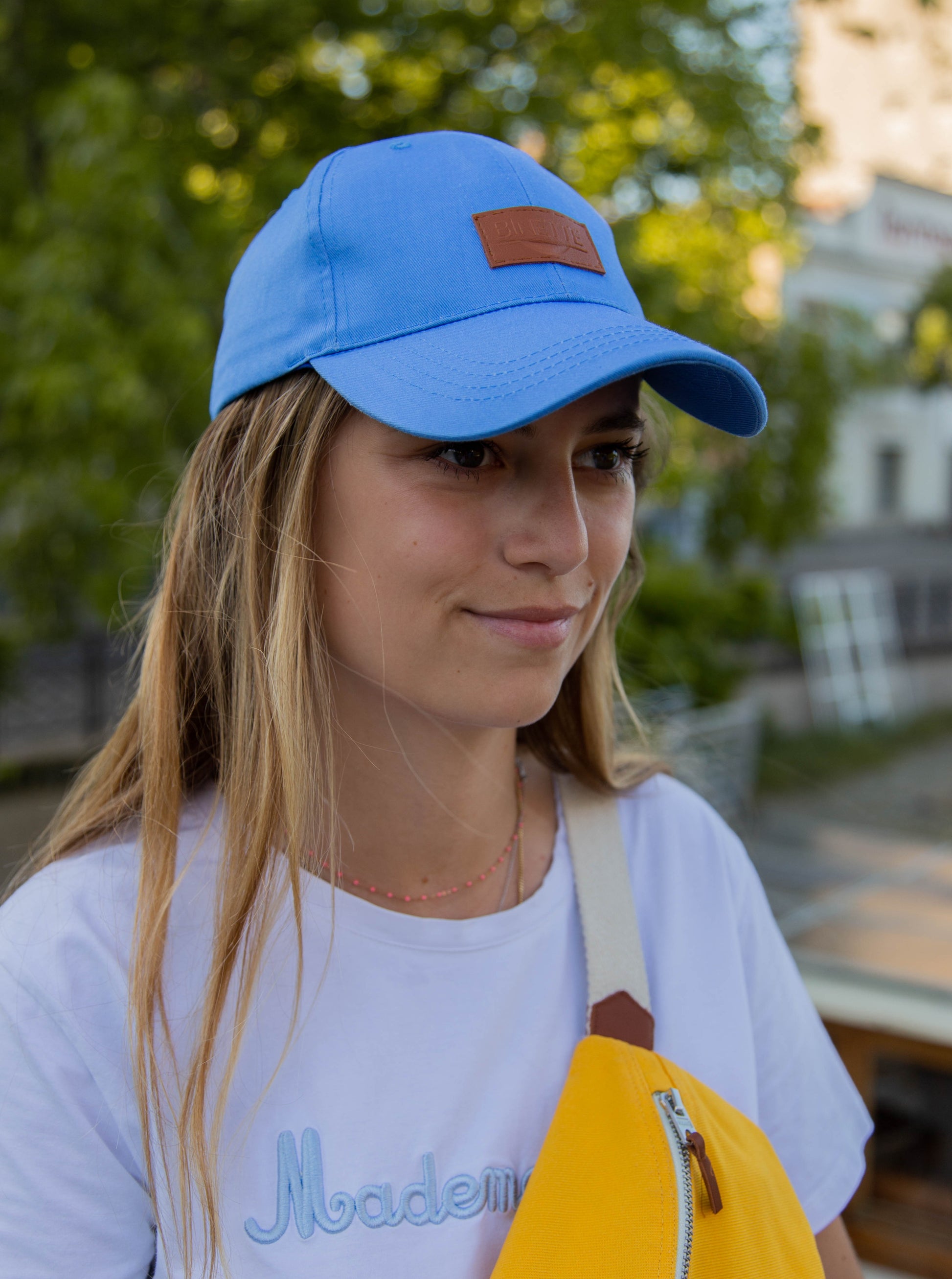 Jeune fille portant une casquette bleue et un sac-banane jaune de la collection binette été, des produits upcyclés et écoresponsables fabriqués par une marque française